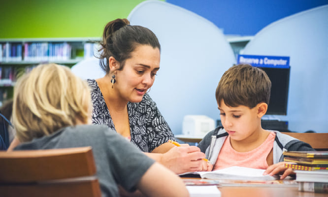 Homework Help - woman helping two children at a table